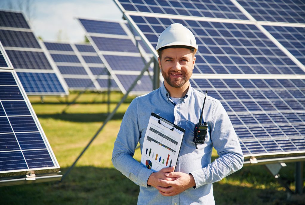 Professional,Adult,Engineer,With,Photovoltaic,Solar,Panels,Outdoors,At,Daytime.